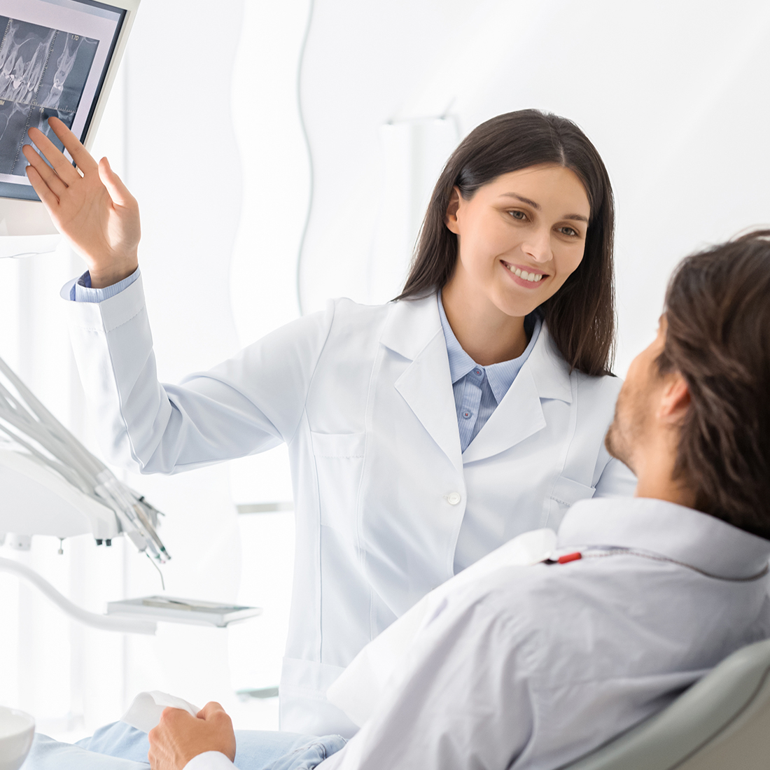 A woman in white lab coat holding up an x-ray.