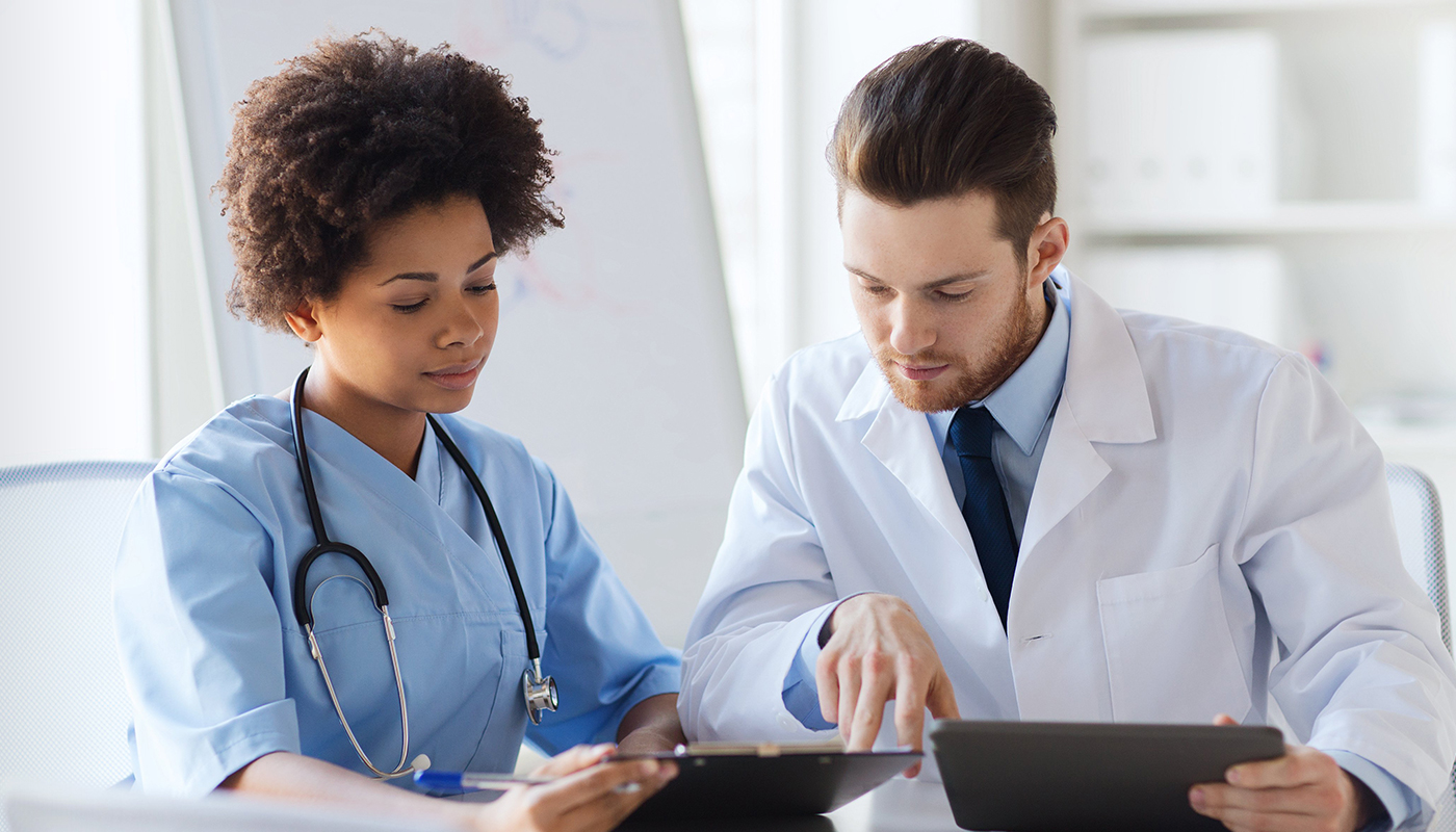 A doctor and nurse looking at something on a tablet.