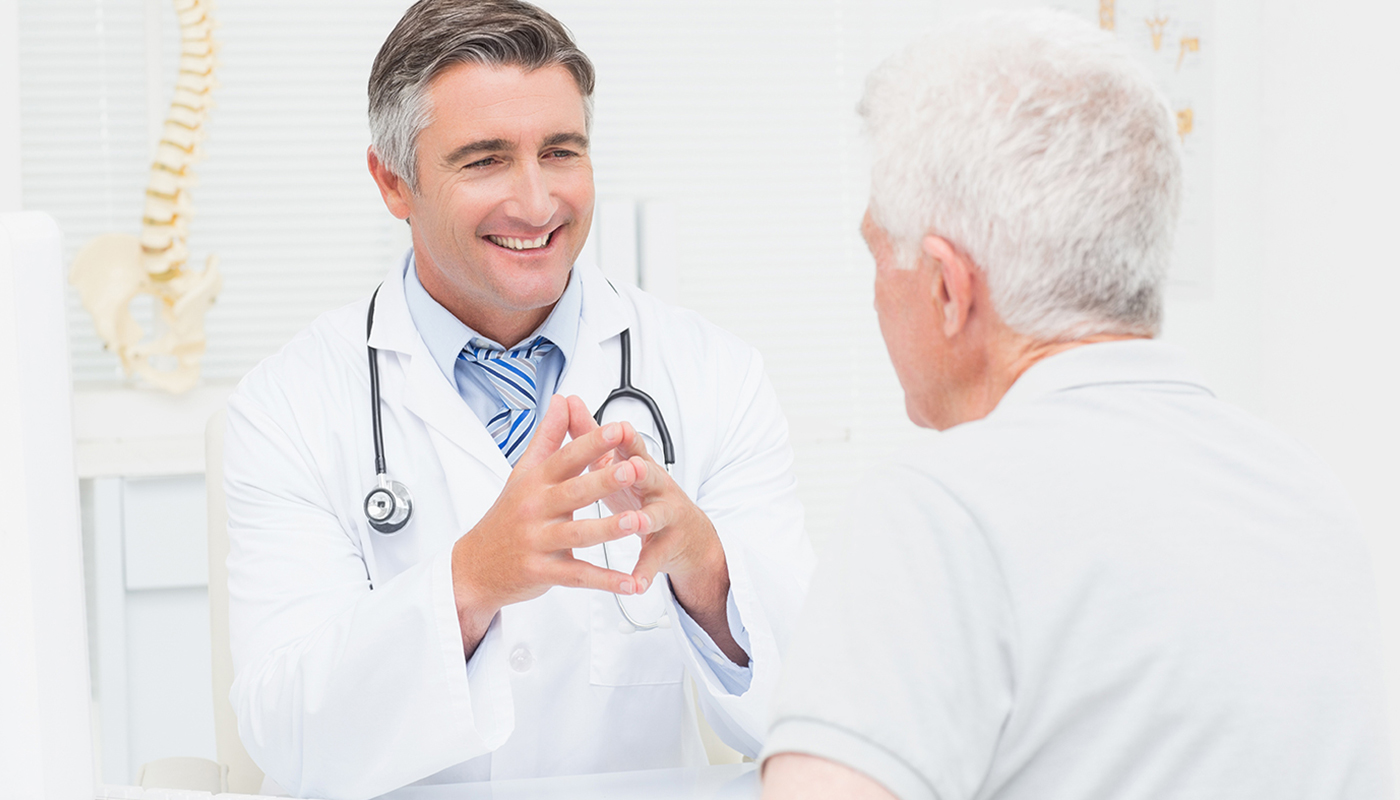 A doctor talking to an older man in front of a mirror.