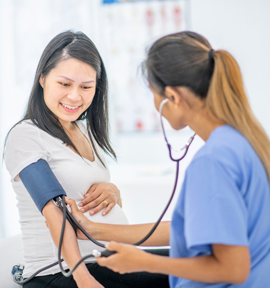 A woman is taking her blood pressure while another person looks on.