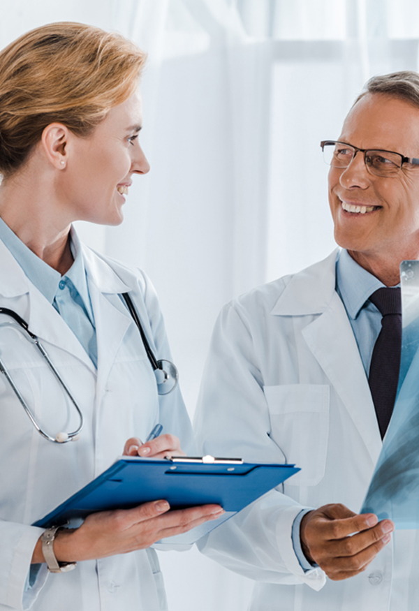 Two doctors are talking to each other while holding a clipboard.