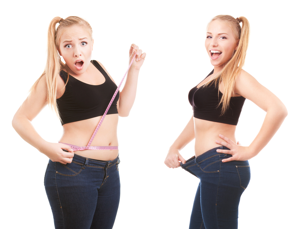 A woman is holding her waist and wearing jeans.