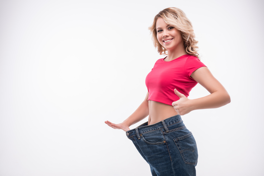 A woman in jeans is showing off her weight loss.