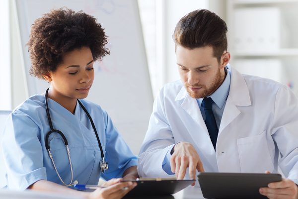 A doctor and nurse looking at something on a tablet.