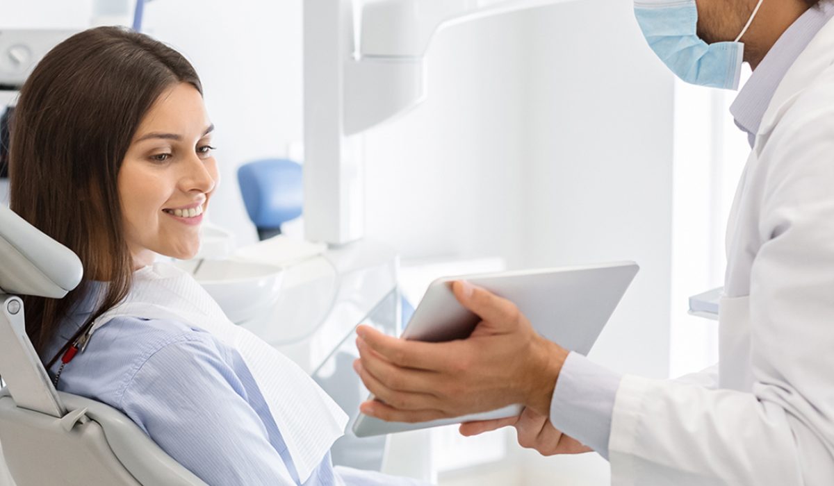 A dentist showing a woman something on her tablet.